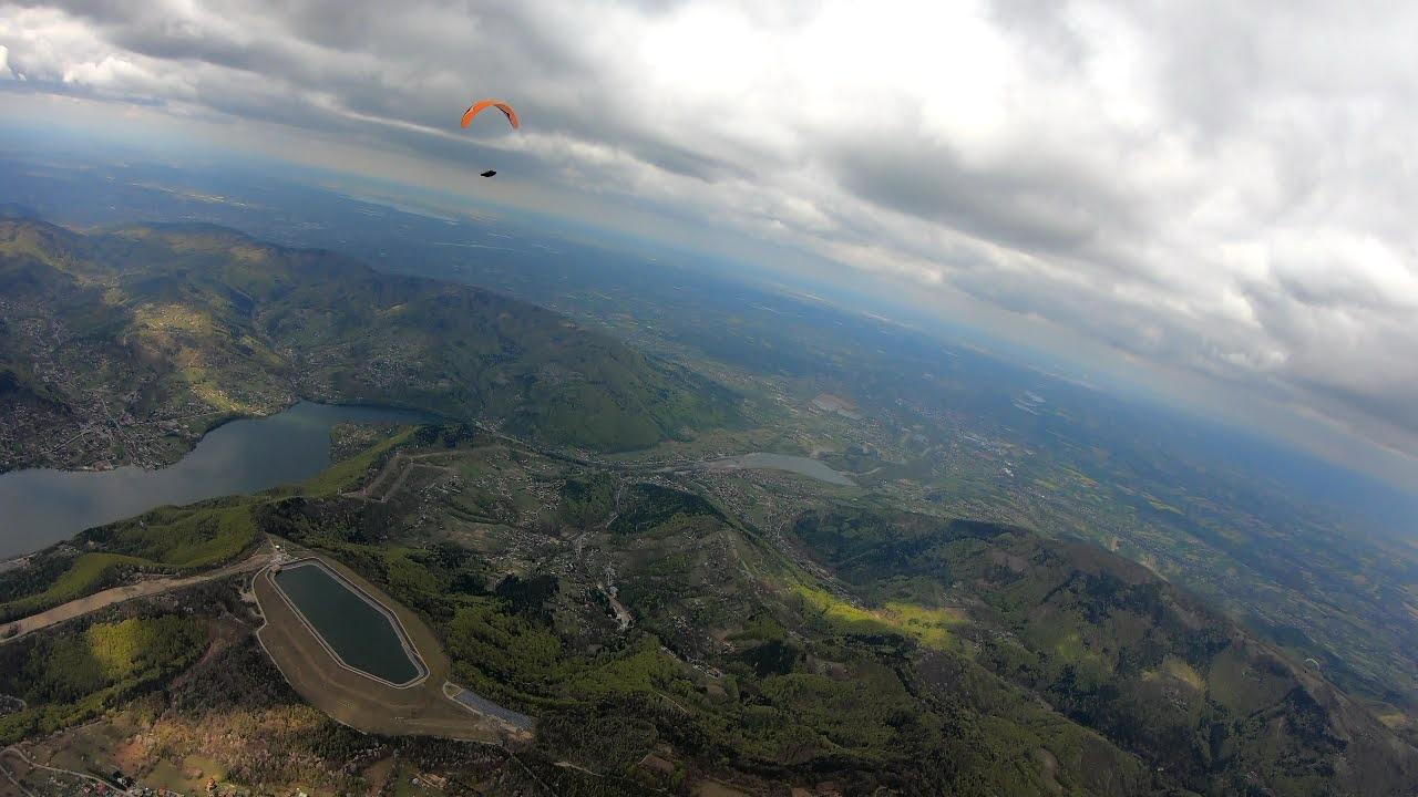 Widok z lotu ptaka na panoramę góry Żar w Beskidzie Małym. Na szczycie góry Żar znajduje się zbiornik wodny elektrowni sczytowo – pompowej. Wokół rozciągają się zbiorniki zaporowe na rzece sole. W oddali widoczny paralotniarz i rozległy widok na przedgórze Beskidu Małego.