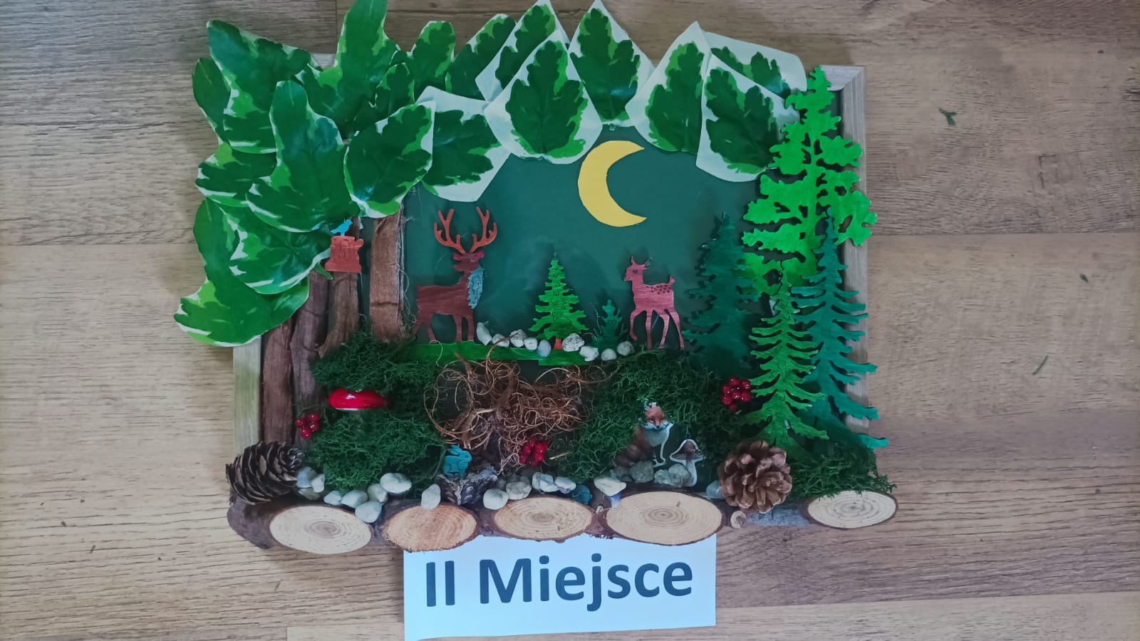 Drugie miejsce, praca plastyczna z użyciem różnych materiałów, przedstawiająca zwierzęta w środowisku leśnym.