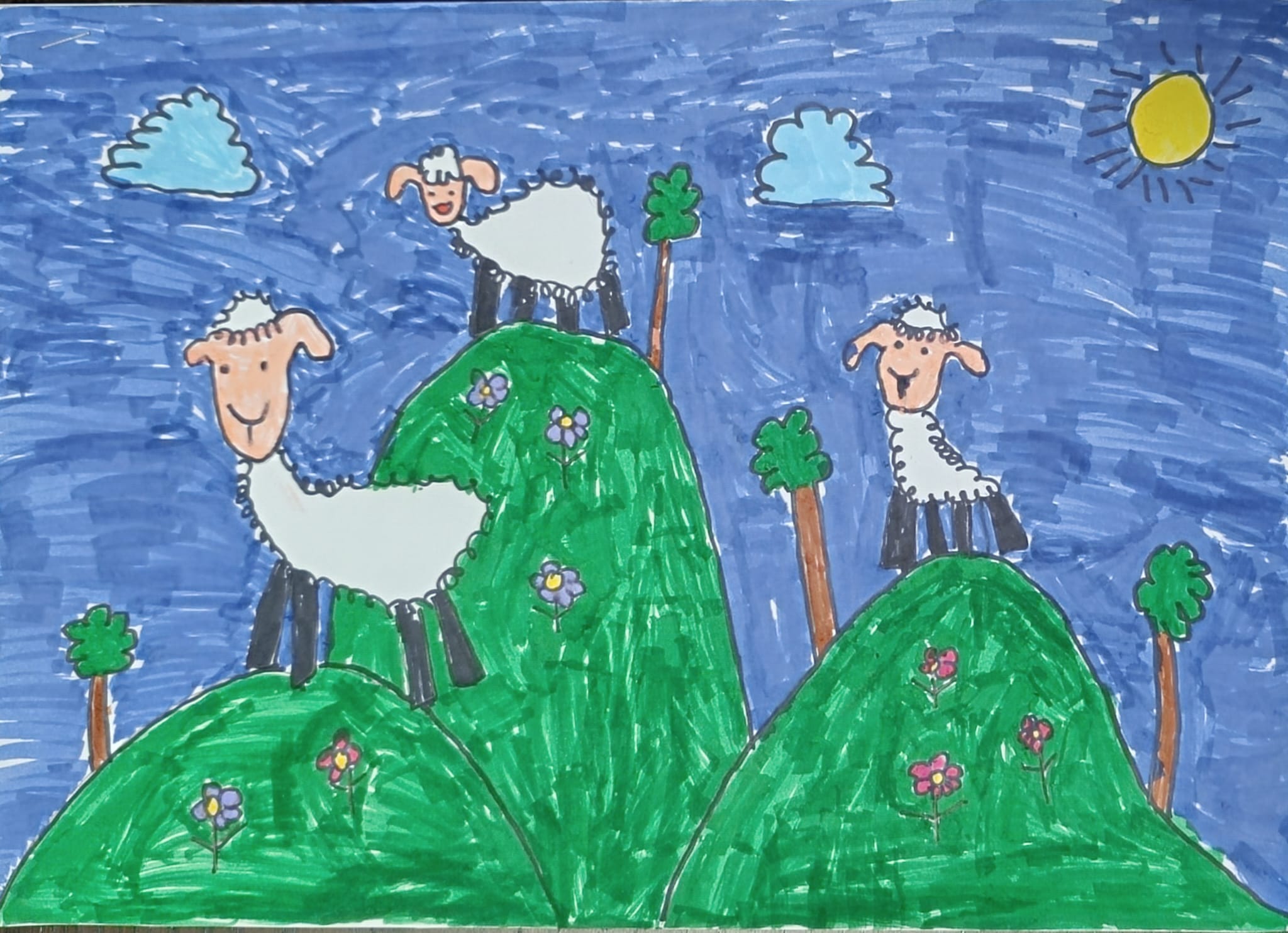 Na rysunku widać trzy owce stojące na zielonych wzgórzach. Wzgórza są ozdobione kolorowymi kwiatkami i kilkoma drzewkami. W tle znajduje się niebieskie niebo z dwoma chmurkami i żółtym słońcem w prawym górnym rogu. Owce mają białe futerko, czarne nogi i różowe pyszczki z uśmiechniętymi minami. 