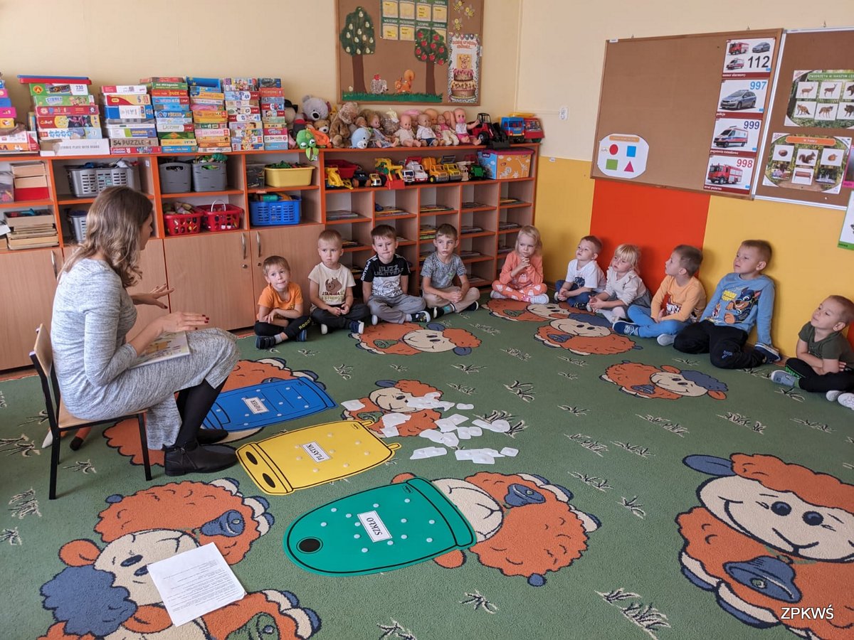 Dzieci siedząc na dywanie słuchają opowiadania pracownika ZPKWŚ Oddziału Biura w Kalinie. 