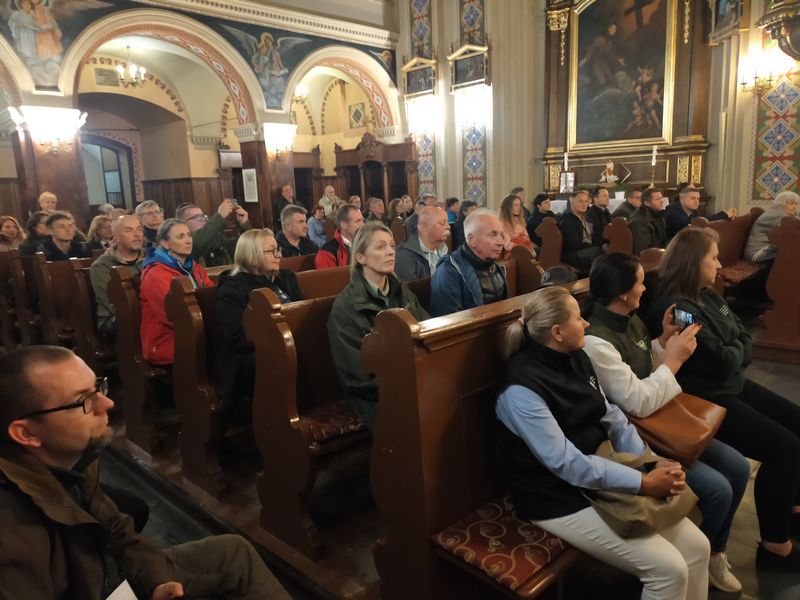 Uczestnicy konferencji siedzą w ławkach w klasztorze wysłuchują historię powstania klasztoru. 