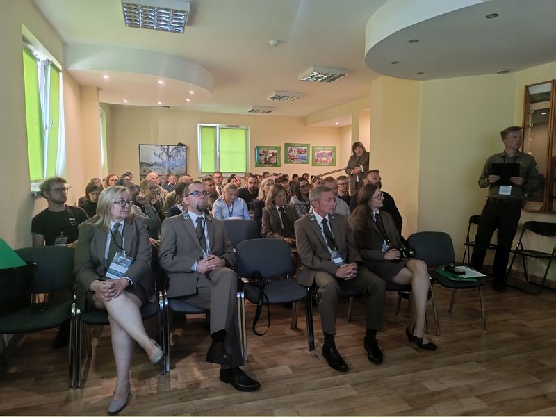 Uczestnicy konferencji podczas sesji referatowej w sali edukacyjnej siedzą w rzędach. 