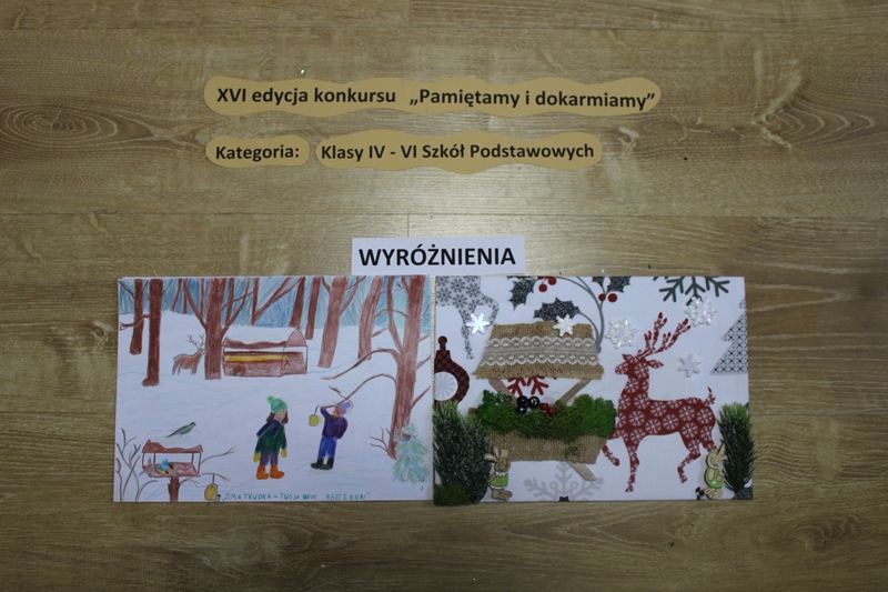 Zdjęcie przedstawia 2 prace, które otrzymały wyróżnienie w kategorii klasy IV-VI szkoły podstawowej. Pierwsze praca przedstawia rysunek dzieci dokarmiających zwierzęta w lesie. Druga praca przedstawia jelenia przy paśniku, użyto różnych materiałów.