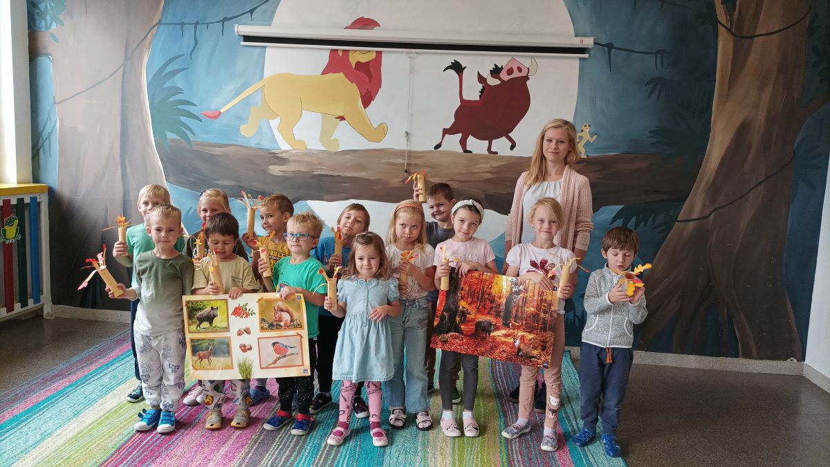 Pracownik ZPKWŚ z grupą przedszkolaków, którzy trzymają zrobione drzewa z papieru.